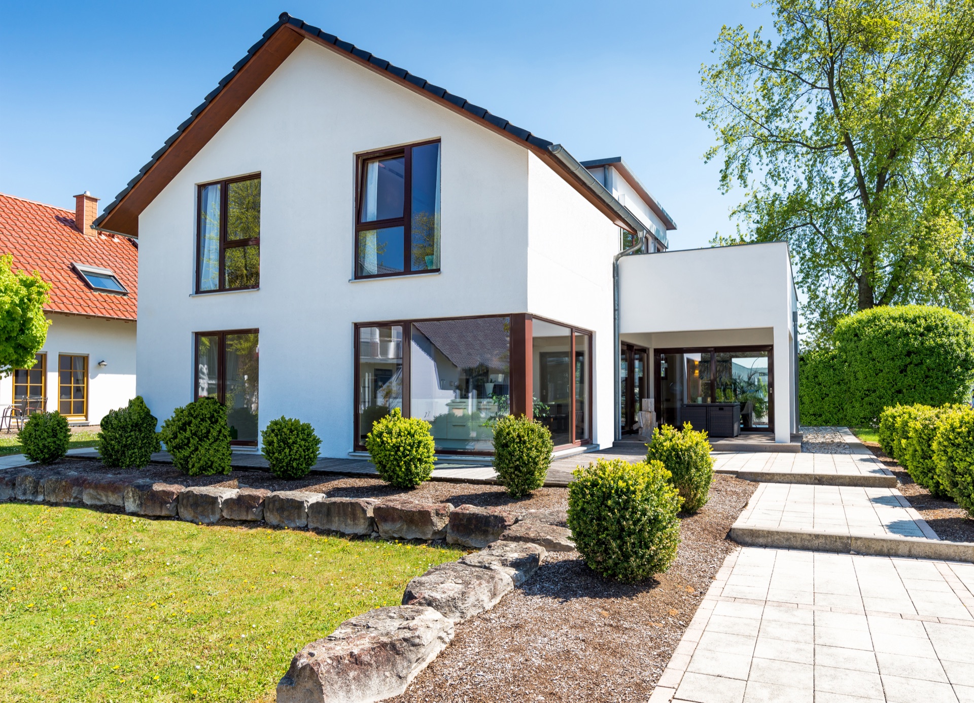 Weißes Einfamilienhaus mit Satteldach und gepflegtem Garten