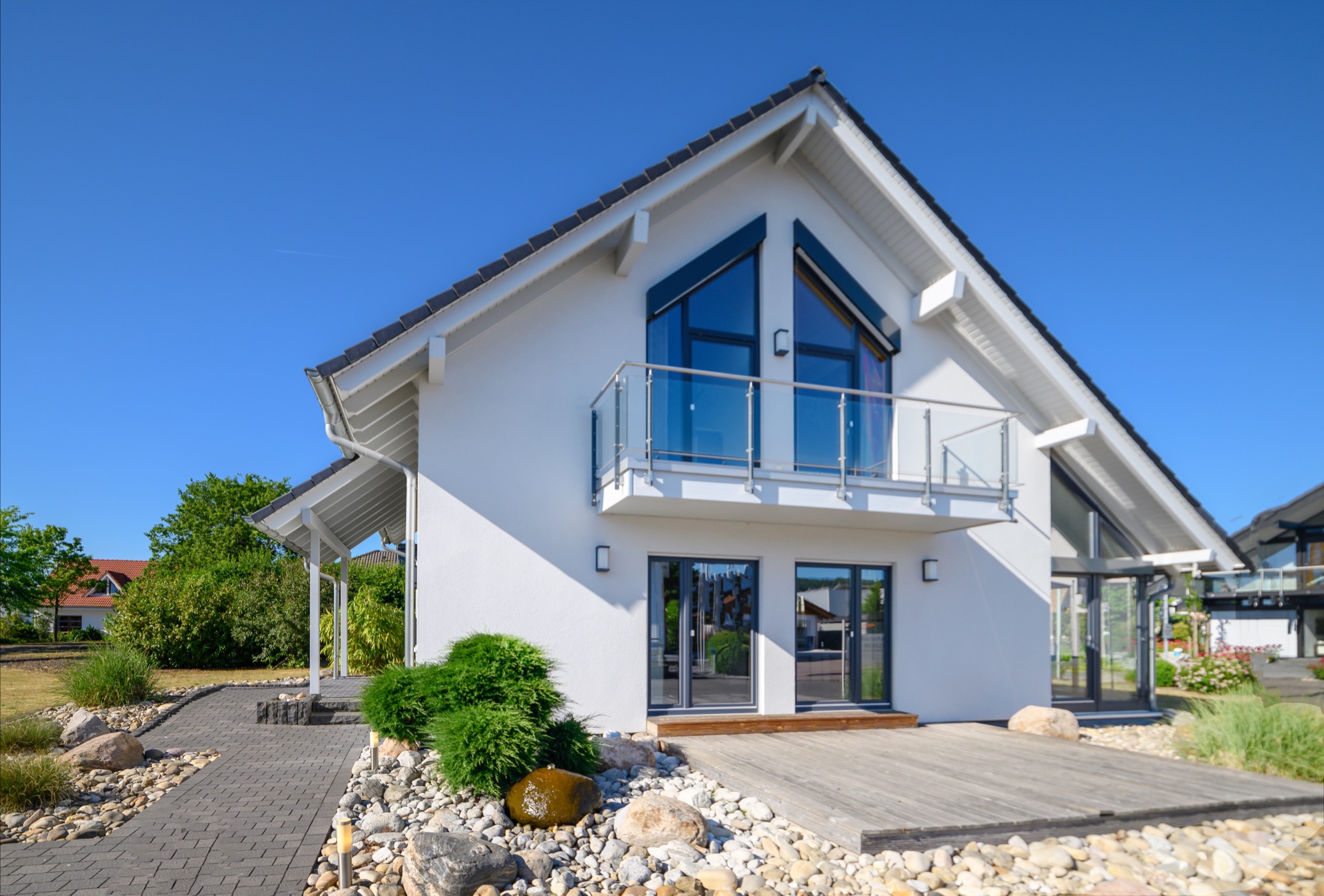 Modernes weißes Haus mit Balkon und Steingarten